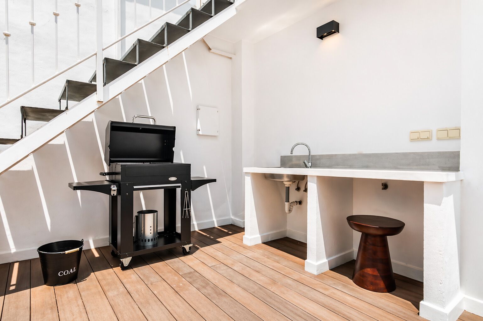 A modern kitchen with a built-in grill, a sink, and a wooden floor.