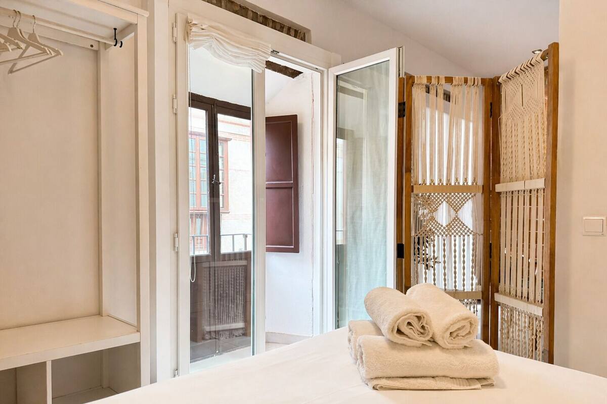 Ein Hotelzimmer mit Bett, Kleiderschrank und einer Tür, die auf einen Balkon führt.