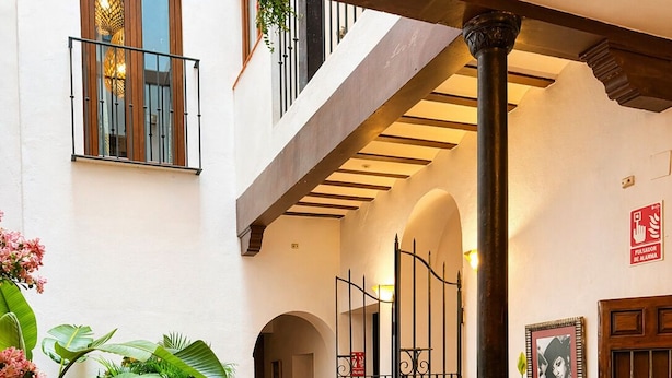 A courtyard with tiled flooring, potted plants, a staircase, and a door. - Prado Suites Apartments (Málaga)