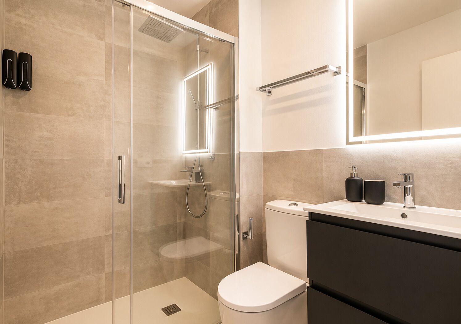 Un bagno moderno con doccia vetrata, un water e un mobile lavabo con specchio.