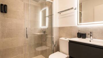 Un bagno moderno con doccia vetrata, un water e un mobile lavabo con specchio.