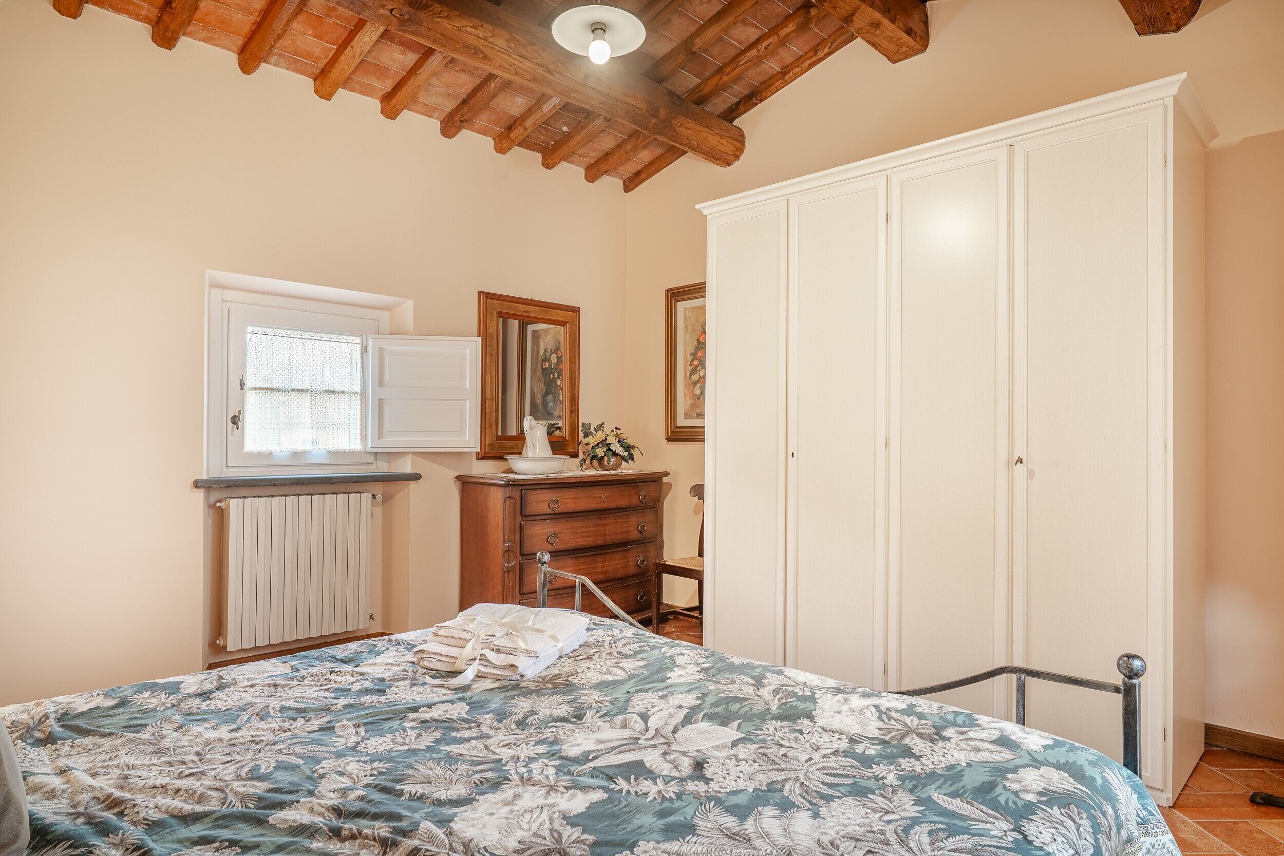 A bedroom with a bed, dresser, wardrobe, and a window with blinds.