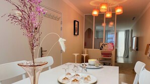 A dining area with a white table set for a meal, a vase with flowers, and a modern chandelier. - "Rose" Atypical Cocoon in the Heart of the Upper Quarter (Sète)