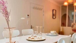 A dining area with a white table, chairs, and a vase with dried flowers. - "Rose" Atypical Cocoon in the Heart of the Upper Quarter (Sète)