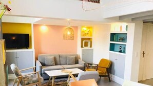 A modern living room with a sofa, chairs, a coffee table, and a TV. - "Zarago 3" T3 Design in Duplex, Clim & Wifi (Sète)
