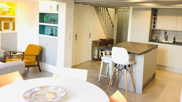 A modern kitchen with white cabinets, a bar area, and a dining space with a round table and chairs. - "Zarago 3" T3 Design in Duplex, Clim & Wifi (Sète)
