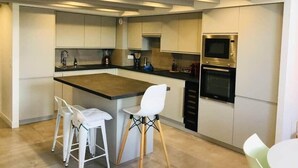 A modern kitchen with a central island, bar stools, and built-in appliances. - "Zarago 3" T3 Design in Duplex, Clim & Wifi (Sète)