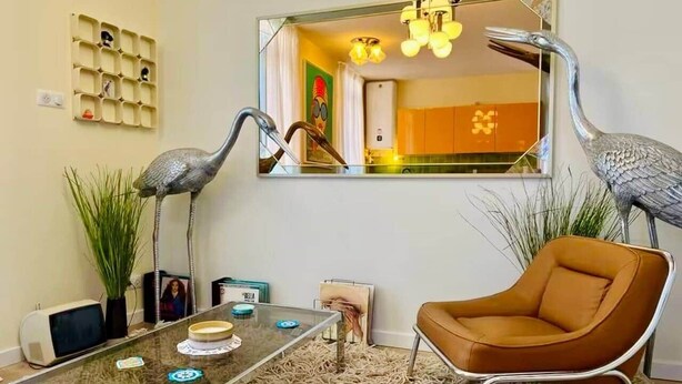 Ein Wohnzimmer mit einem Glastisch, einem braunen Ledersessel und zwei dekorativen Vogelplastiken.