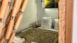 Ein Zimmer mit einem Bett, weißen Kissen, einem Fellüberwurf und einem Bild an der Wand.