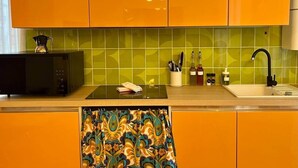Eine Küche mit orangenen Schränken, einer Mikrowelle, einem Spülbecken und einem gemusterten Handtuch.