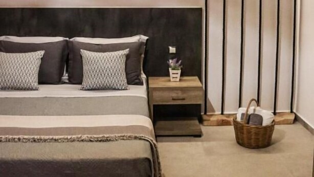 Un dormitorio con cama, mesitas de noche, lámpara colgante y pared con líneas verticales.