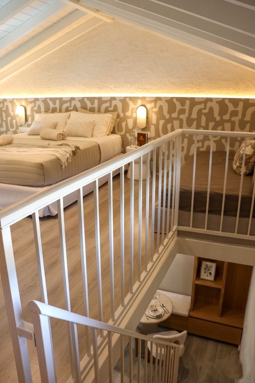 Un dormitorio con una cama, barandilla blanca y una escalera que baja a un nivel inferior.