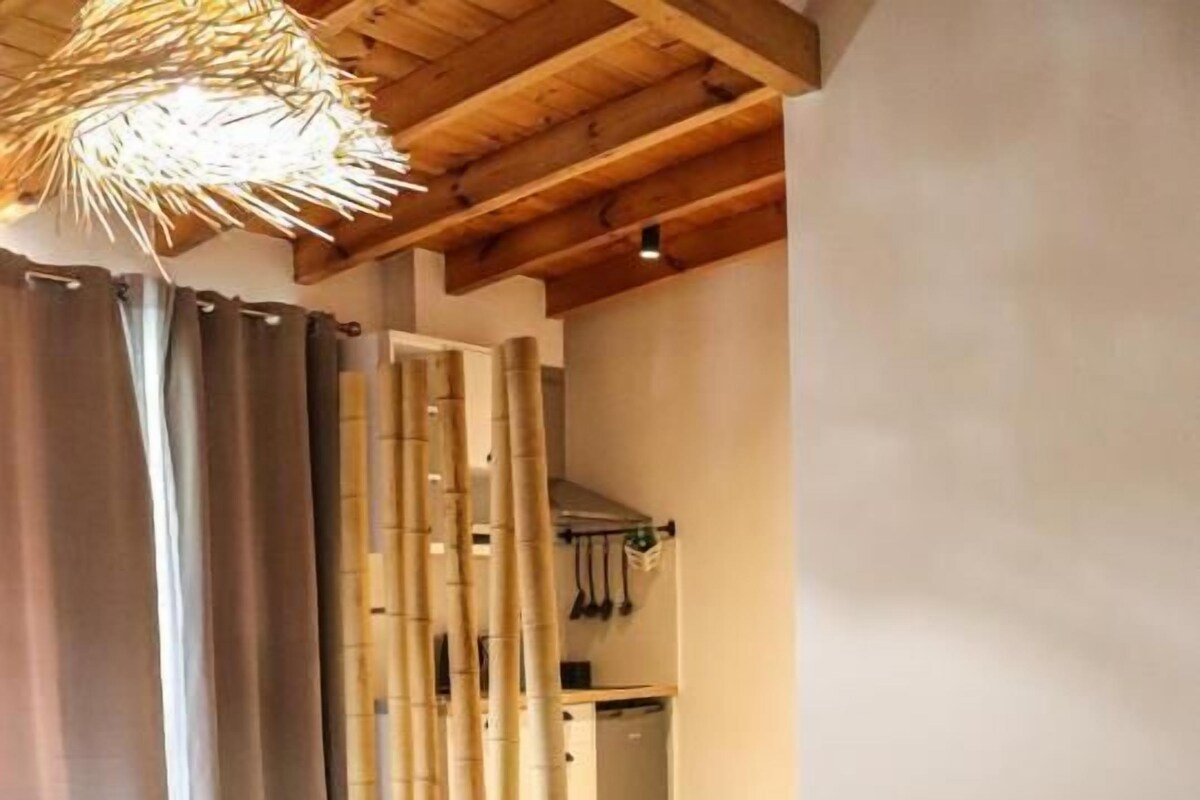 A bedroom with a bed, curtains, a bamboo wall, and a hanging light fixture.