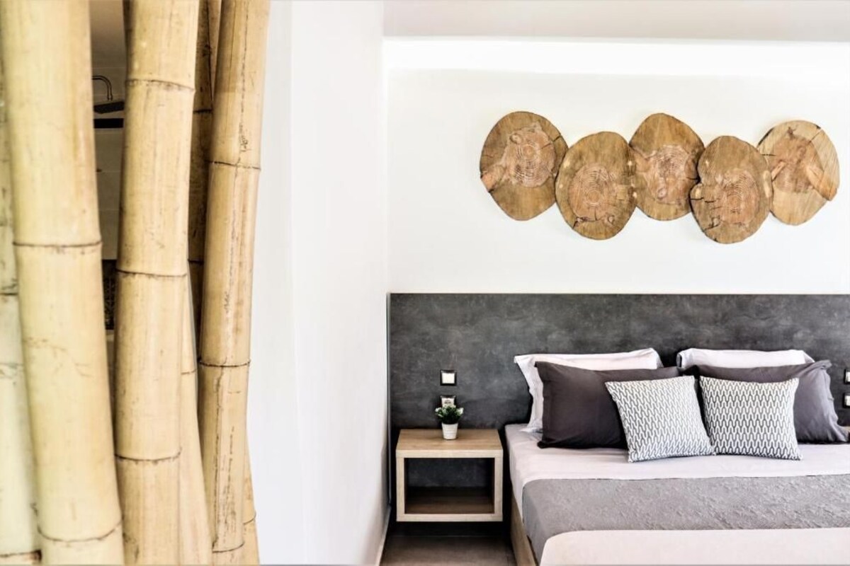 A bedroom with a bed, a nightstand, a wall-mounted decorative piece, and a curtain.