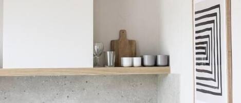 Una cocina moderna con encimera de hormigón, armarios de madera y una lámpara colgante.