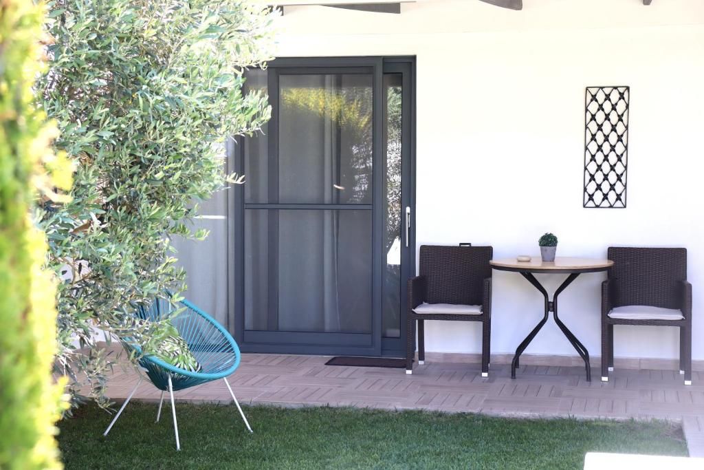 A patio area with a black sliding door, two wicker chairs, a small round table, and a potted plant.