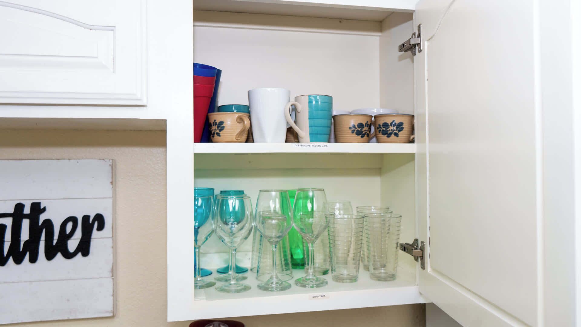A cabinet with shelves holding various glassware and ceramic mugs.
