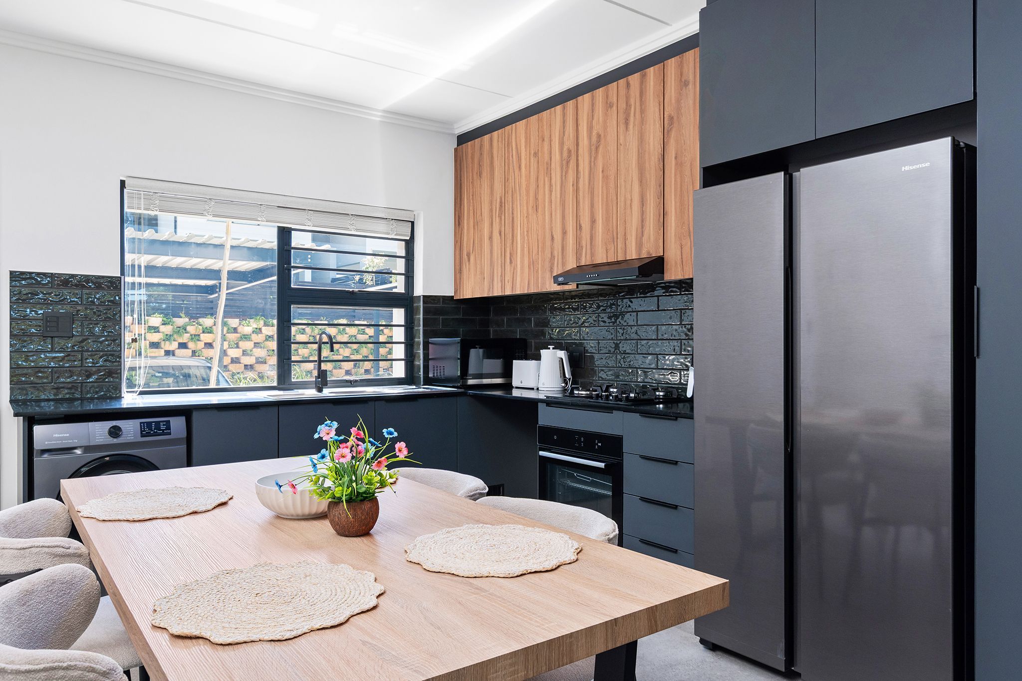 A modern kitchen with a wooden table, a built-in oven, and a large refrigerator.