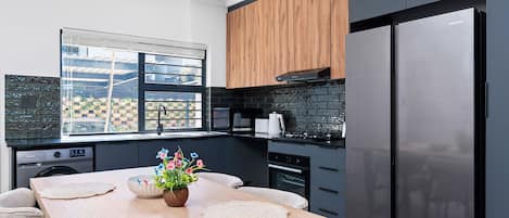 A modern kitchen with a wooden table, a built-in oven, and a large refrigerator.
