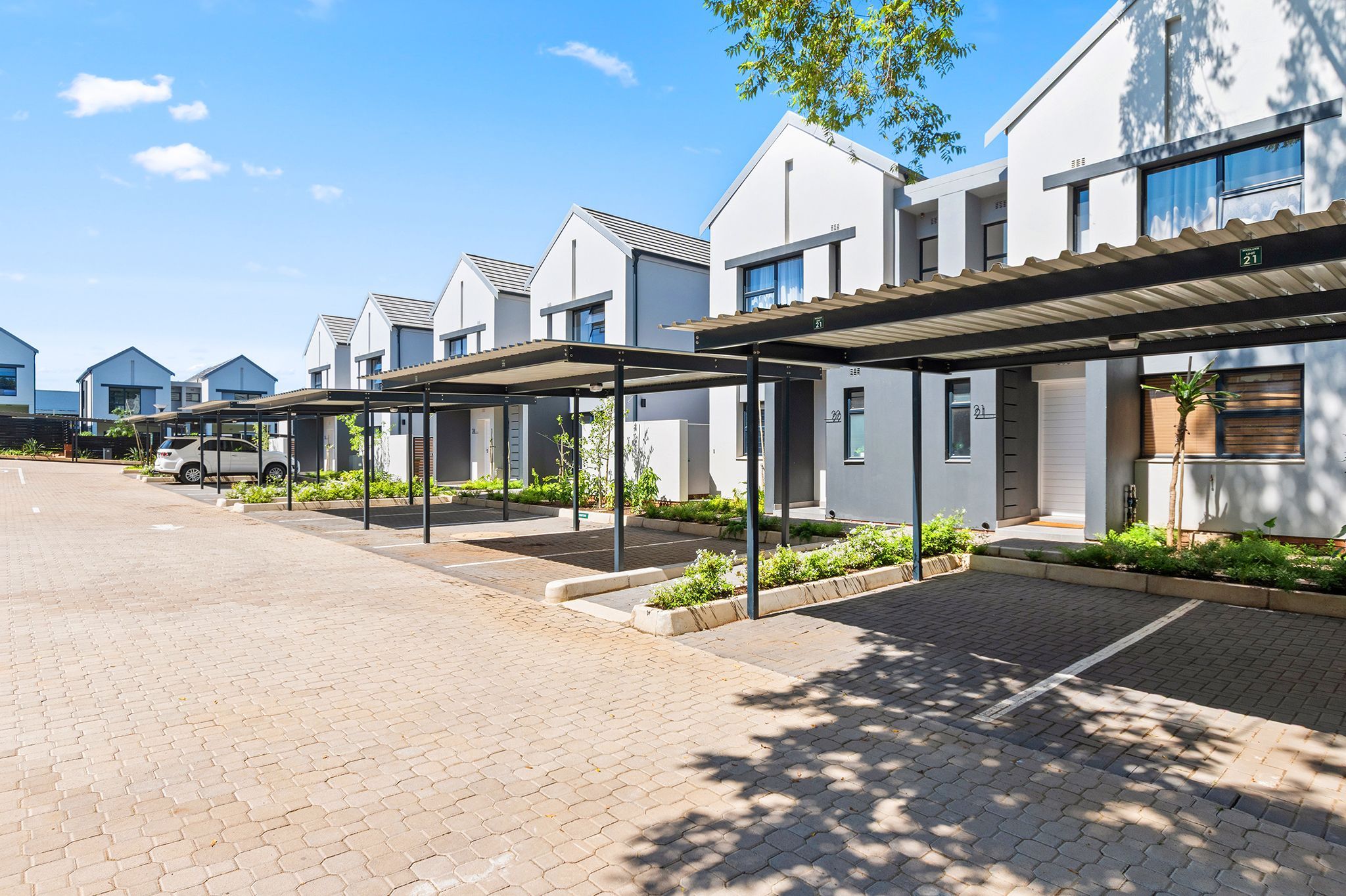 A row of modern, white buildings with covered walkways and a paved driveway.