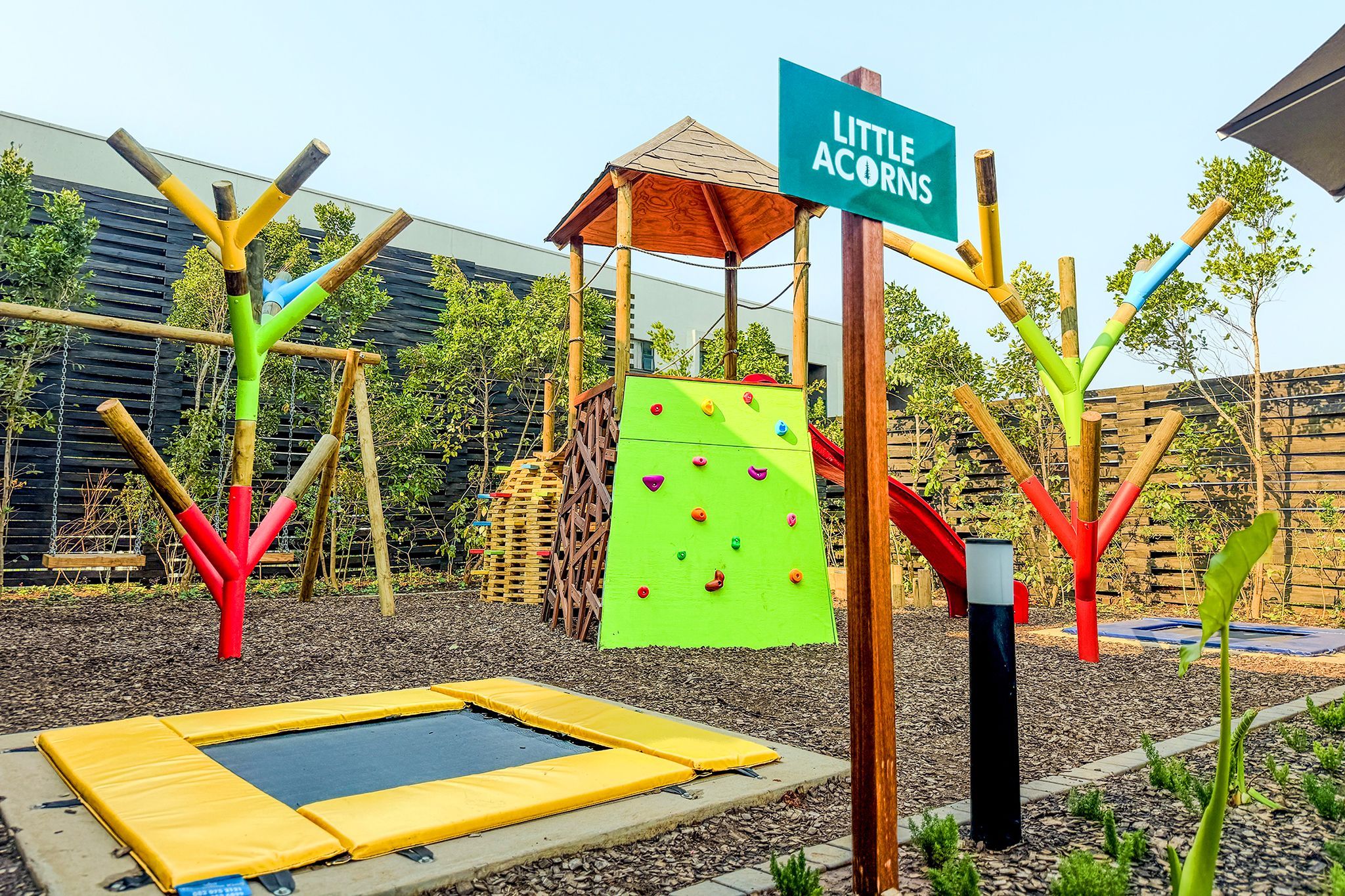 Ein Spielplatz mit Klettergerüst, Rutsche und Trampolin.