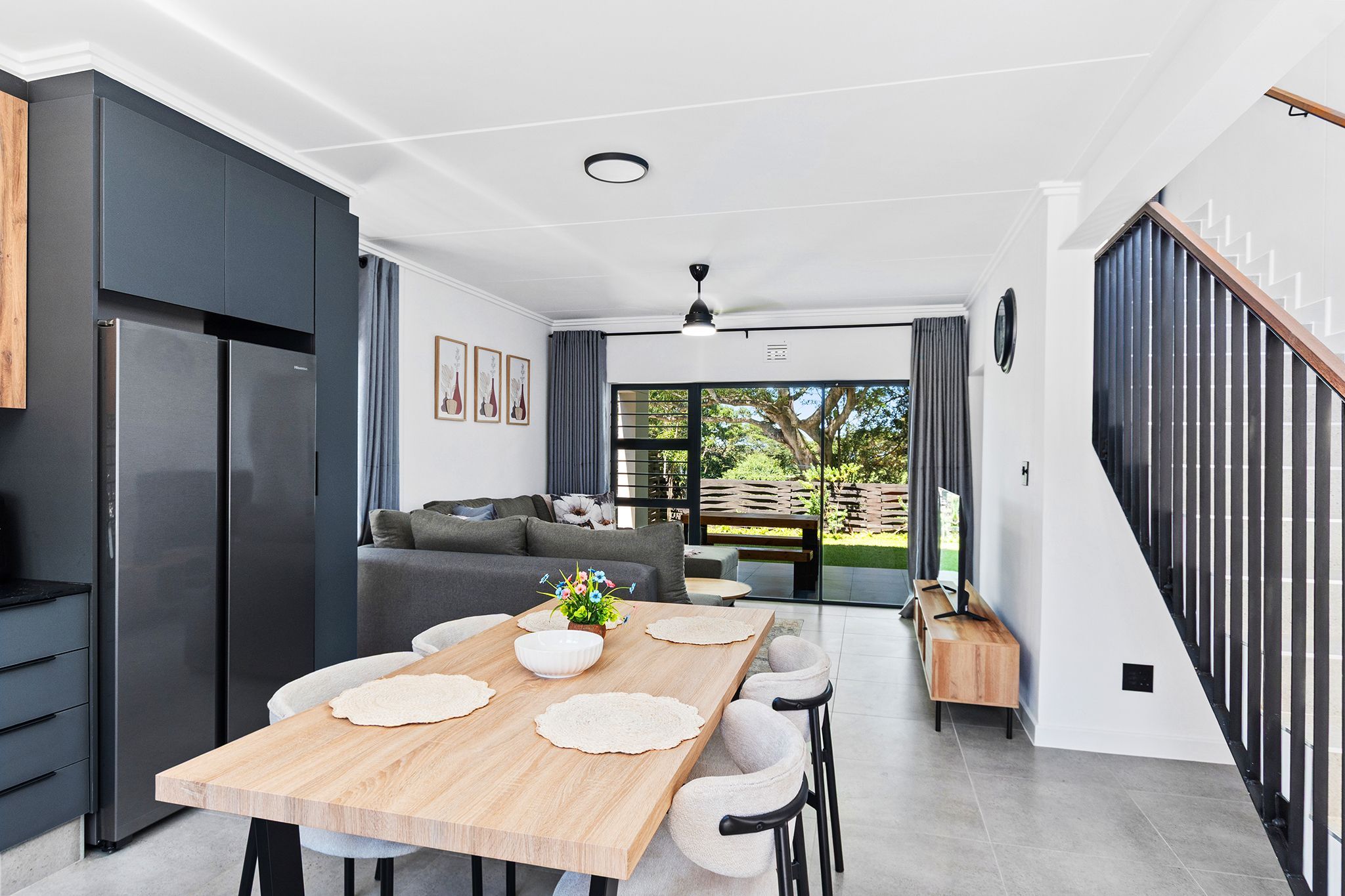 A modern kitchen with a dining area, a staircase, and a view of the outdoors.