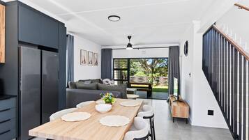A modern kitchen with a dining area, a staircase, and a view of the outdoors.