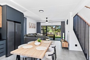 A modern kitchen with a dining area, a staircase, and a view of the outdoors.