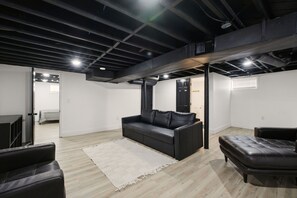Ein modernes Wohnzimmer mit einer schwarzen Ledersofa, einem weißen Teppich und Holzboden.