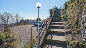 Uma escadaria que sobe uma colina gramada, com um poste de luz e um carro estacionado por perto.