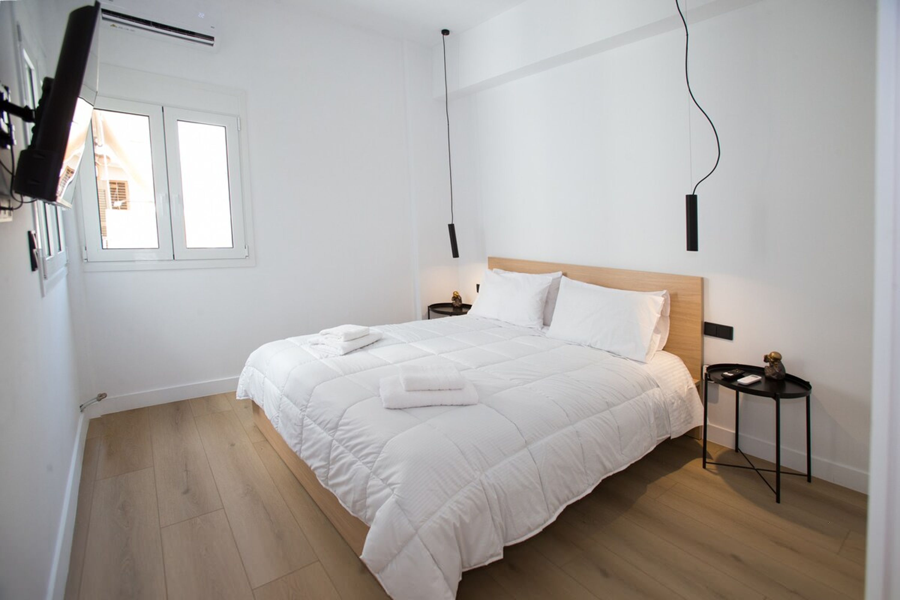 A neatly made bed with white bedding, a wooden headboard, and a bedside table with a small decorative item.