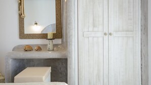 Ein Schlafzimmer mit Bett, Schminktisch mit Spiegel, weißem Kleiderschrank und flachbildfernseher an der Wand.