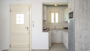 A compact kitchen with white cabinets, a stainless steel refrigerator, and a small countertop. - My Villa Naxos II (Naxos)