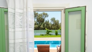 A room with a view of a swimming pool, a wooden chair, and a green door. - My Villa Naxos II (Naxos)