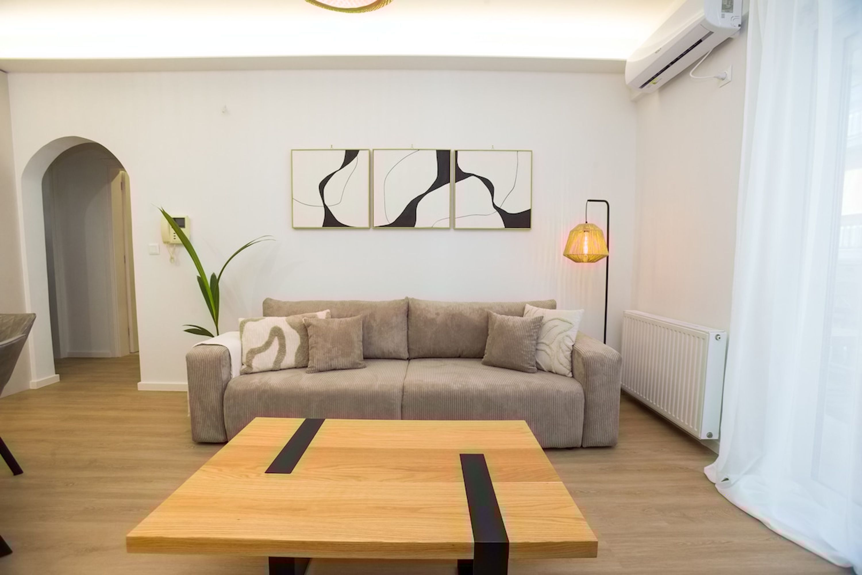 A modern living room with a beige sofa, a wooden coffee table, and abstract wall art.