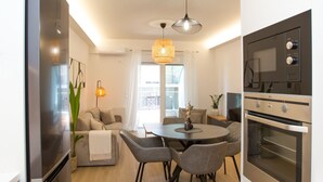 A modern kitchen with a dining area, built-in appliances, and a pendant light. - K11 Apartment (Athens)