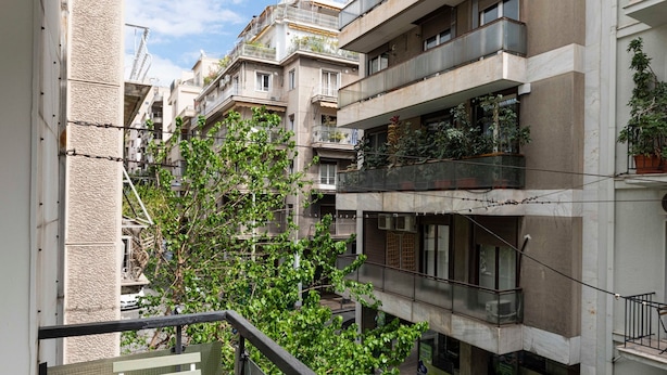 Un immeuble résidentiel à plusieurs étages, doté de balcons, dont certains sont ornés de plantes.