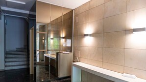 Une salle de bain moderne avec une paroi en verre, un lavabo blanc et un mur recouvert de carreaux beiges.