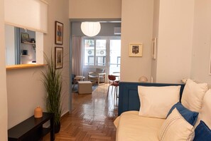 Un salon moderne avec un canapé, une table basse et, au fond, un coin repas.