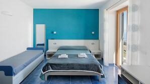 Un dormitorio con cama, una banca, una mesita de noche y una ventana con cortinas.