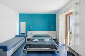 A bedroom with a bed, a bench, a bedside table, and a window with curtains. - 'Volare Sea View Room' with Sea View, Wi-Fi and Air Conditioning (Pianillo)