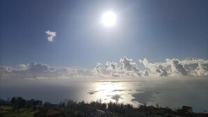 Vista costera con cielo despejado, sol brillante y mar tranquilo.