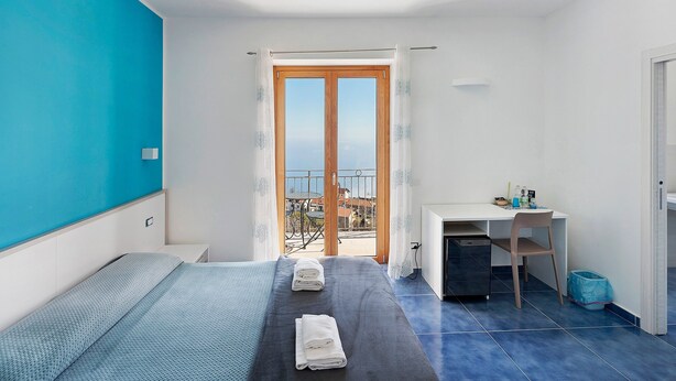 Un dormitorio con cama, escritorio y vista al mar.