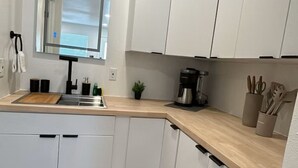 Een moderne keuken met witte kasten, een houten aanrecht, een spoelbak en een koffiezetapparaat.