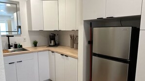 Een moderne keuken met witte kasten, een roestvrijstalen koelkast en een houten aanrecht.