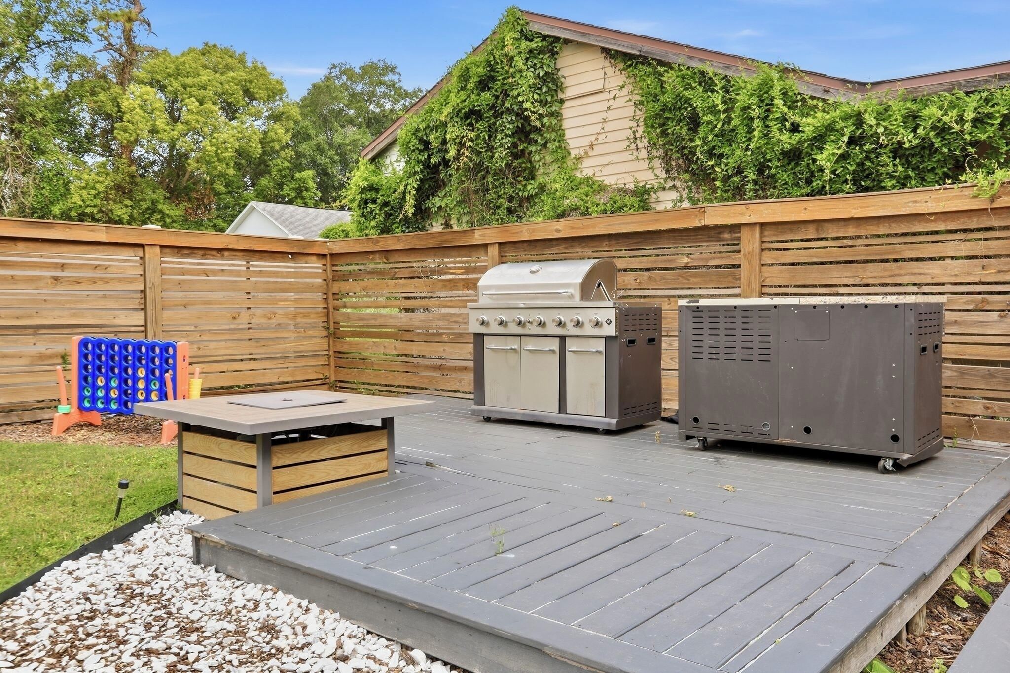 Une terrasse extérieure équipée d’un barbecue, d’une table et d’un espace salon.