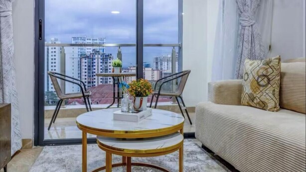 A modern living room with a balcony, a round table, and a sofa. - Charming apartment in beautiful Nairobi Kilimani with easy city access (Nairobi)