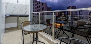 A modern balcony with a glass table and chairs, a kitchen area with marble backsplash, and a cityscape view under a cloudy sky. - Charming apartment in beautiful Nairobi Kilimani with easy city access (Nairobi)