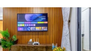 A reception area with a wooden panel wall, a flat-screen TV, a reception desk, and a potted plant. - Charming apartment in beautiful Nairobi Kilimani with easy city access (Nairobi)