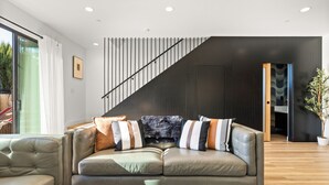 Ein modernes Wohnzimmer mit einer Ledersofa, einem Couchtisch mit Schachspiel und einer Treppe mit dunkler Wand und Holzgeländer.